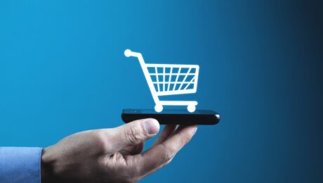 Hand holding a phone with a shopping icon. Online shopping